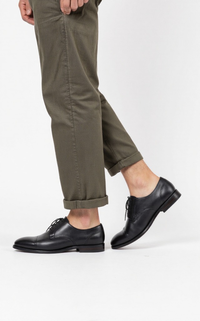 A male model wearing Men's shoes, against a white background, with a close   up of the feet